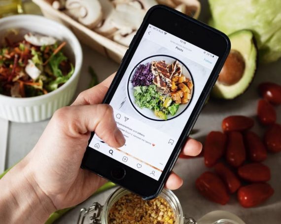 Person takes photo of healthy salad ingredients for social media in kitchen.